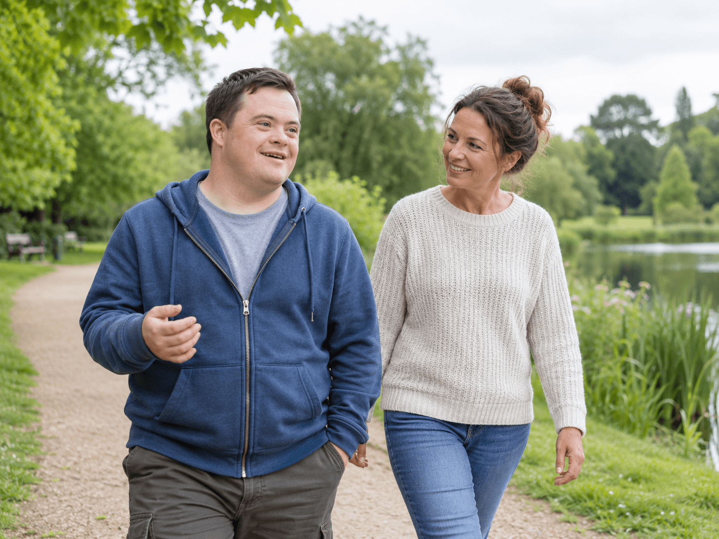 An adult and support worker walking together in a park
